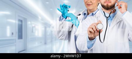 Eine Ärztin in einem Laborkittel bereitet eine Spritze für die Impfung vor, während ein männlicher Arzt Stockfoto