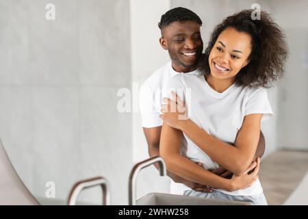 Liebevolles afroamerikanisches Paar umarmt sich in ihrem Badezimmer drinnen Stockfoto