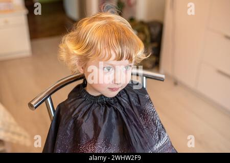 Glückliches kleines Mädchen zeigt ihren trendigen neuen Haarschnitt im Schönheitssalon. Stockfoto