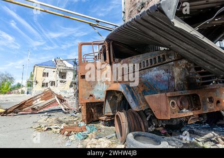 Ein verbranntes Militärauto auf der Straße der zerstörten Stadt Stockfoto