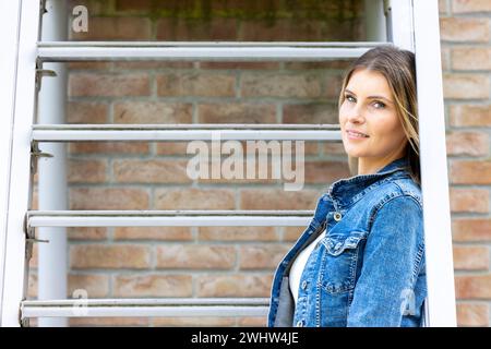 Stilvolle blonde Millennial-Frau auf Metalltreppe Stockfoto