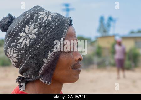 Ein afrikanischer Dorfmann trägt eine Ohr-Klappe Trapper-Hut Mongolische Schneeflocken-Pom-Beanie Stockfoto