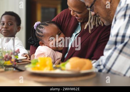 afroamerikanische Enkelin und Großmutter, die sich beim Thanksgiving-Dinner umarmen Stockfoto