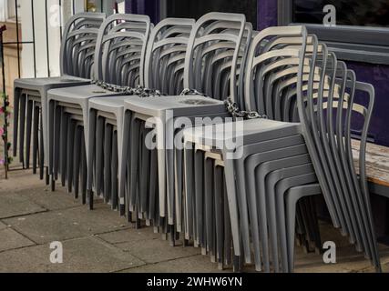 An sonnigen Tagen stehen neben der Terrasse des Cafés stapelbare silbergraue Plastikstühle. Detaillierte Darstellung von Musterstapel Kunststoffstühle, Platz für Text, Sel Stockfoto