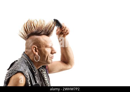 Punk mit einem mohawk, der sein Haar isoliert auf weißem Hintergrund kämmt Stockfoto