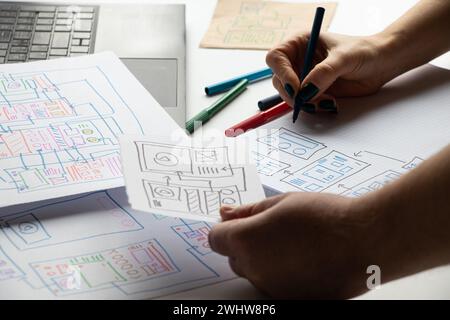 Entwicklung und Skizzen auf Papier einer individuellen mobilen Anwendung für den Desktop und die Hände des Designers, Grafikdesign, Designerarbeit Stockfoto