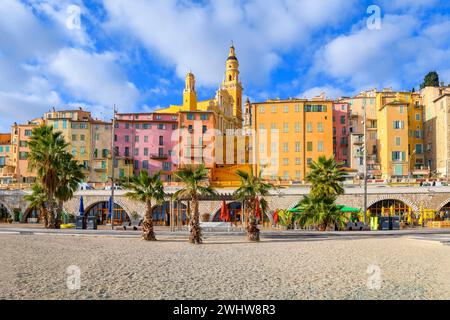 Blick vom Strand Plage des Sablettes und der Promenade auf die farbenfrohe Altstadt von Menton France, die Kathedrale, den Glockenturm und die Stufen zur Basilika Stockfoto