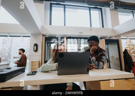 Zwei junge Berufstätige, ein Mann und eine Frau, arbeiten an einem modernen Büroarbeitsplatz mit Enthusiasmus und Fokus zusammen. Stockfoto