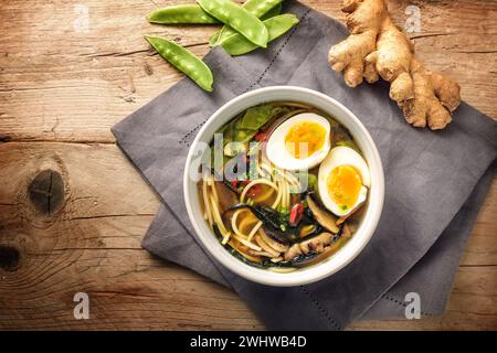 Miso-Suppe mit Nudeln, Nori-Algen, Schneeroben, Ingwer und einem Ei in einer Schüssel auf einem rustikalen Holztisch, Blick von oben, Kopie Stockfoto