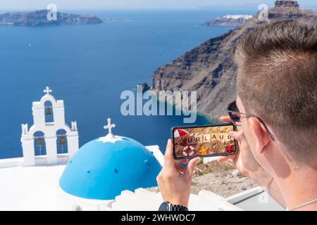 11. Februar 2024: Symbolischer Bilderurlaub, junger Mann im Urlaub, fotografiert mit seinem Smartphone in Griechenland, vor dem blauen Meer und der wunderschönen Landschaft. Auf dem Handy ein Bild vom Strand mit dem Text: URLAUB. FOTOTAGE *** Symbolbild Urlaub, junger Mann im Urlaub, macht ein Foto mit seinem Smartphone in Griechenland, vor dem blauen Meer und schöner Landschaft. Auf dem Handy ein Bild vom Strand mit dem Text: URLAUB. FOTOMONTAGE Stockfoto