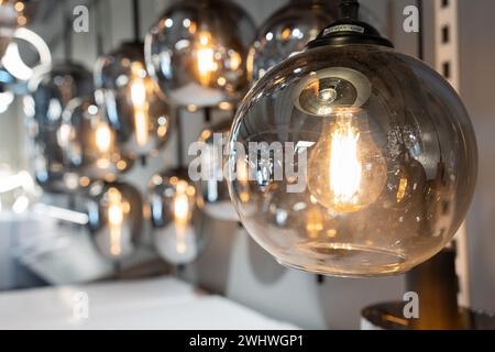 Vintage-Wolfram-Glühfaden mehrere Lampen unterschiedlicher Größe und Stil, die von der Decke hängen. Runde glühende Wolframlampe. Stockfoto