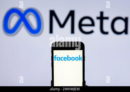 In dieser Fotoabbildung wird das Facebook-Logo auf dem Bildschirm eines Mobiltelefons mit dem Meta-Logo im Hintergrund angezeigt. Stockfoto