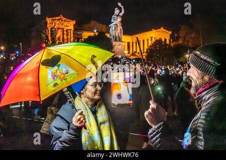 Teilnehmerin mit Regenbogenschirm, Lichtermeer für Demokratie, Kundgebung gegen Rassismus, Antisemitismus und Hetze, Theresienwiese, München, 11. Februar 2024 Deutschland, München, 11. Februar 2024, Teilnehmende mit Laterne und buntem beleuchteten Regenbogenschirm unterhalb der Bavaria, Lichtermeer für Demokratie, Kundgebung gegen Rassismus, Antisemitismus und Hetze, CA. 100,000 Teilnehmer mit Lichtern auf der Theresienwiese, ab 18 Uhr, Veranstalter Fridays for Future und ein breites Aktionsbündnis zivilgesellschaftlicher Initiativen und Organisationen, dabei Lichterkette e.V., Bellevue di Mon Stockfoto