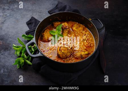 Traditionelles, scharfes indisches Huhn Madras Curry Rogan Josh mit Drumsticks serviert als Nahaufnahme in einer nordischen Schüssel Stockfoto