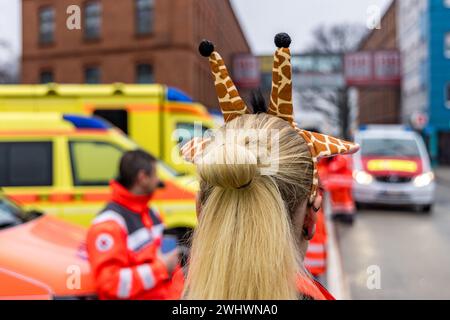 Cottbus, Deutschland. Februar 2024. Rettungsdienste des Deutschen Roten Kreuzes treffen sich, um heute die Prozession fröhlicher Menschen zu sichern. Ab 1,11 Uhr präsentieren rund 4000 Teilnehmer 60 dekorierte Lkw aus der Region, Berlin und Sachsen. Tausende von Besuchern beobachten die größte Karnevalsparade Ostdeutschlands vom Straßenrand aus. Vermerk: Frank Hammerschmidt/dpa/Alamy Live News Stockfoto