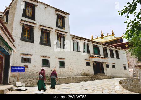 Zwei Frauen gehen eine Kopfsteinpflasterstraße im Sera-Kloster entlang, das sich direkt außerhalb von Lhasa, der Autonomen Region Tibet von China, befindet. Stockfoto