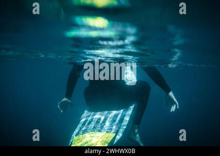 Unterwasserfoto eines halb versunkenen Surfers auf seinem Brett, von hinten gesehen Stockfoto