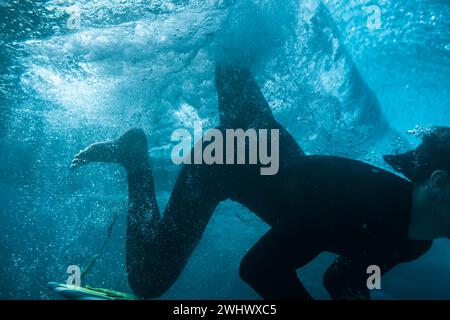 Unterwasserbild eines Surfers, der in eine vorbeiziehende Welle taucht Stockfoto