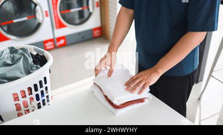 Hausmann mit Korb und schmutziger laundryÂ gewaschener Kleidung im Waschraum. Waschen machineÂ im Wäschereigeschäft Stockfoto