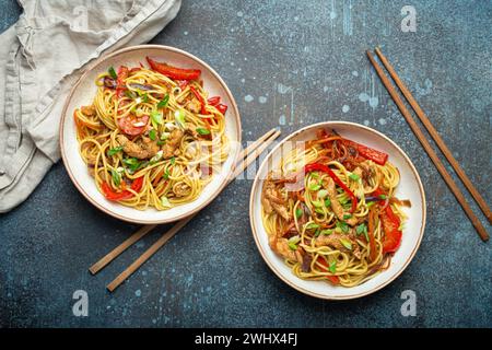 Zwei Schüsseln mit Chow mein oder Lo mein, traditionelle chinesische Rührnudeln mit Fleisch und Gemüse, serviert mit Essstäbchen Top V Stockfoto