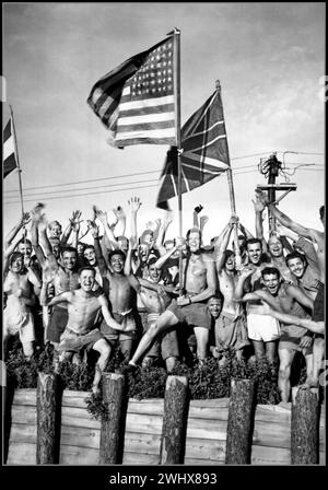 Japanische Kriegsgefangene aus dem 2. Weltkrieg Gaunt verbündete Kriegsgefangene im Aomori-Lager in der Nähe von Yokohama und feuerte die Retter der US Navy an. Die Flaggen der Vereinigten Staaten, Großbritanniens und Hollands schwenken. Japan, 29. August 1945. (Marineblau) Stockfoto