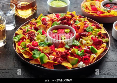 Nachos geladen. Mexikanische Nacho-Chips mit Rindfleisch, mit Guacamolensauce Stockfoto