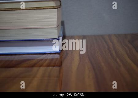 Nicht bearbeitetes Foto des Buchstapels auf einem Holztisch vor grauem Hintergrund. Stockfoto