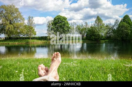 Beine und Füße vor ruhigen Süßwasser Teich entspannen Stockfoto