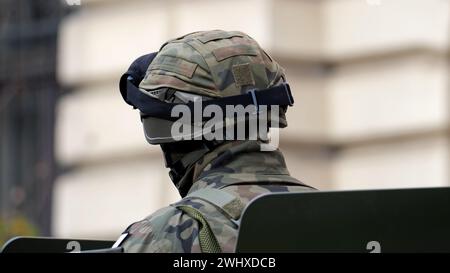 Ein einziger anonymer Soldat in einer generischen grünen Tarnuniform, Helm und Schutzbrille, von hinten gesehen, Nahaufnahme des Kopfes, einer nicht erkennbar Stockfoto