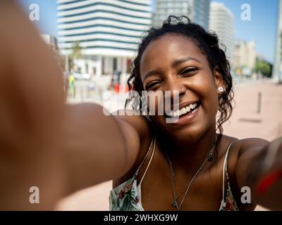 POV einer glücklichen afroamerikanischen jungen Frau, die während eines Urlaubs ein Selfie in einer Stadt macht Stockfoto