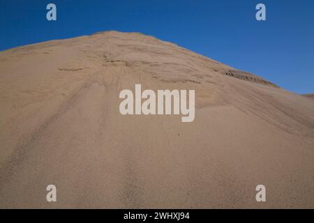 Hügel aus feinem hellbraunem Sand in kommerzieller Sandgrube. Stockfoto