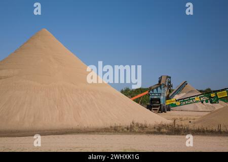 Haufen von feinem, braunem Sand und Stapeln von Förderbändern in gewerblichen Sandgruben. Stockfoto