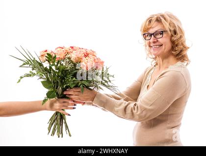 Reife, schöne blonde Frau bekommt einen Blumenstrauß, isoliert Stockfoto