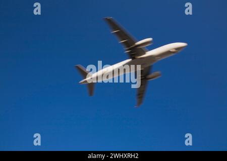 Unterseitenansicht eines gewerblichen Jet-Flugzeugs im Flug mit Bewegungseffekt. Stockfoto