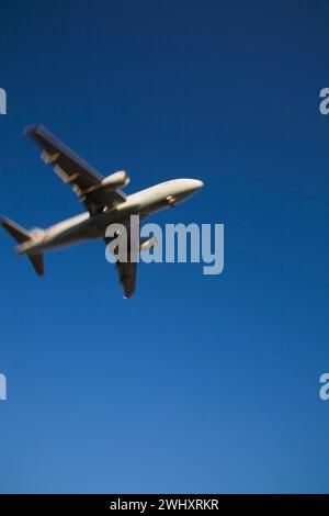 Unterseitenansicht eines gewerblichen Jet-Flugzeugs im Flug mit Bewegungseffekt. Stockfoto