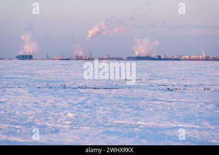 Rauch aus den Stadtröhren am Horizont und eine schneebedeckte Feldstadt Stockfoto