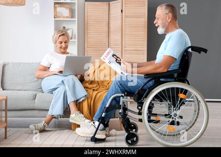 Reife Frau und ihr Ehemann im Rollstuhl ruhen zu Hause aus Stockfoto