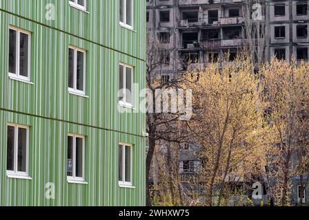 Neu gebautes Haus vor dem Hintergrund der zerstörten und verbrannten während der Kämpfe in der Ukraine Stockfoto