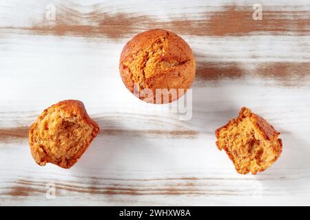 Orangefarbene Muffins auf einem rustikalen hölzernen Küchentisch, einfaches Backen, über dem Kopf Stockfoto