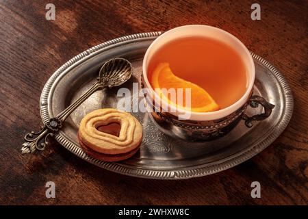 Orangentee mit Keksen, eine Tasse auf einem Vintage-Tablett auf einem dunklen rustikalen Hintergrund Stockfoto