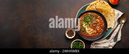 Traditionelles indisches Punjabi-Gericht Dal Makhani mit Linsen und Bohnen in schwarzer Schüssel serviert mit Naan-Fladenbrot, frischem Koriander und Stockfoto