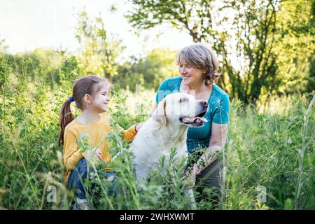 Grauhaarige Großmutter und süße kleine Enkelin gehen mit ihren Hunden zusammen im Park Stockfoto