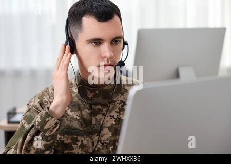 Militärdienst. Junger Soldat in Kopfhörern, der im Büro arbeitet Stockfoto