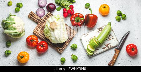 Frisches Gemüse mit Schneidebrettern aus Holz und Messer auf weißem Küchentisch mit Blick von oben. Kochen vegetarisches Essen von Heal Stockfoto