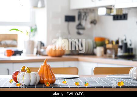 Dekor der weißen klassischen Küche mit Kürbissen, Girlanden, Latern für Halloween und Ernte mit Hausfigur. Herbststimmung in Stockfoto