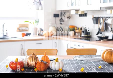 Dekor der weißen klassischen Küche mit Kürbissen, Girlanden, Latern für Halloween und Ernte mit Hausfigur. Herbststimmung in Stockfoto