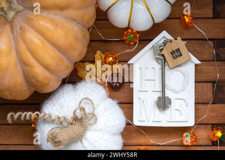 Gemütliches Layout auf einem hölzernen Hintergrund aus Latten mit Kürbissen, Herbstblättern, einem Haus und Schlüsseln - Herbststimmung, Halloween, Gehäuse, re Stockfoto