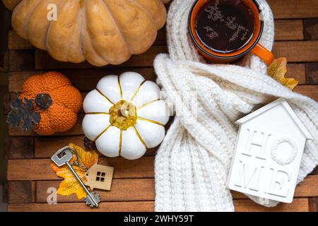 Gemütliches Layout auf einem hölzernen Hintergrund aus Latten mit Kürbissen, Herbstblättern, einem Haus und Schlüsseln - Herbststimmung, Halloween, Gehäuse, re Stockfoto