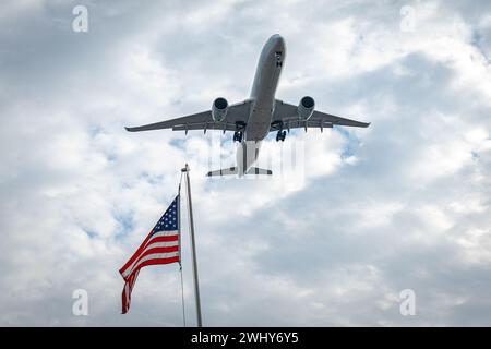 Flugzeug Airbus A350 fliegt am Himmel vor dem Hintergrund der amerikanischen Flagge Stockfoto