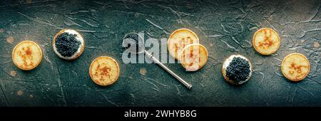 Blinis mit schwarzem Kaviar und Frischkäse Panorama auf schwarzem Schieferboden Stockfoto